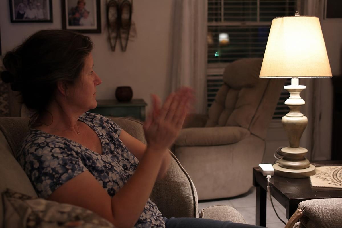 A woman clapping to turn on a lamp using The Clapper sound-activated switch
