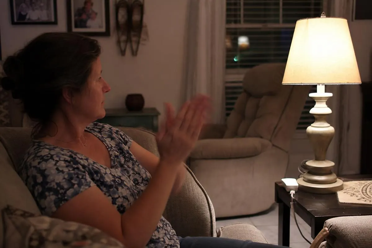 A woman clapping to turn on a lamp using The Clapper sound-activated switch